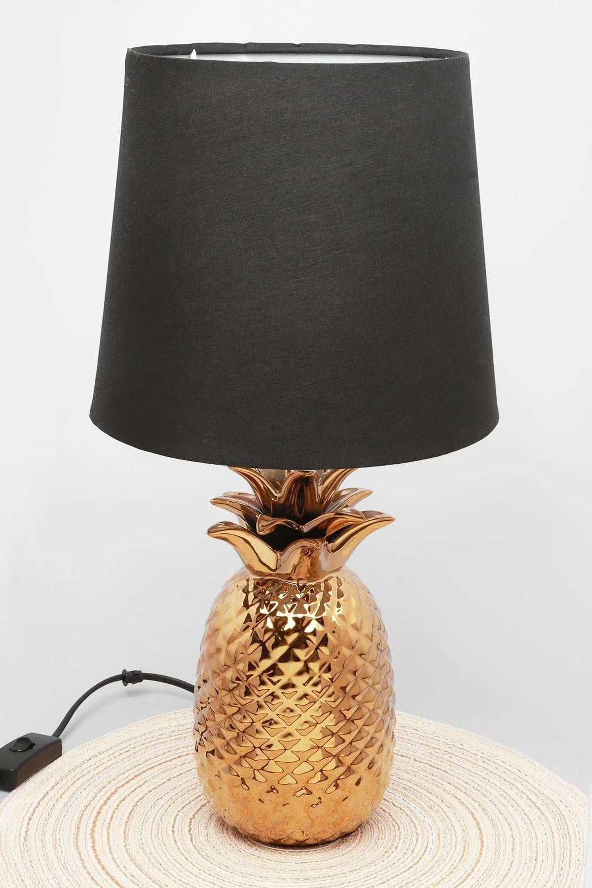 Styling a home office desk with light - Ananas Dore gold pineapple table lamp with black shade, set on a working desk beside books | G Decor