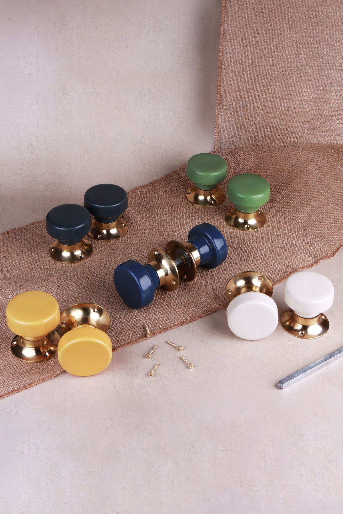 Five pairs of flat ceramic mortice door knobs on polished brass roses in charcoal, sage green, navy blue, yellow and cream