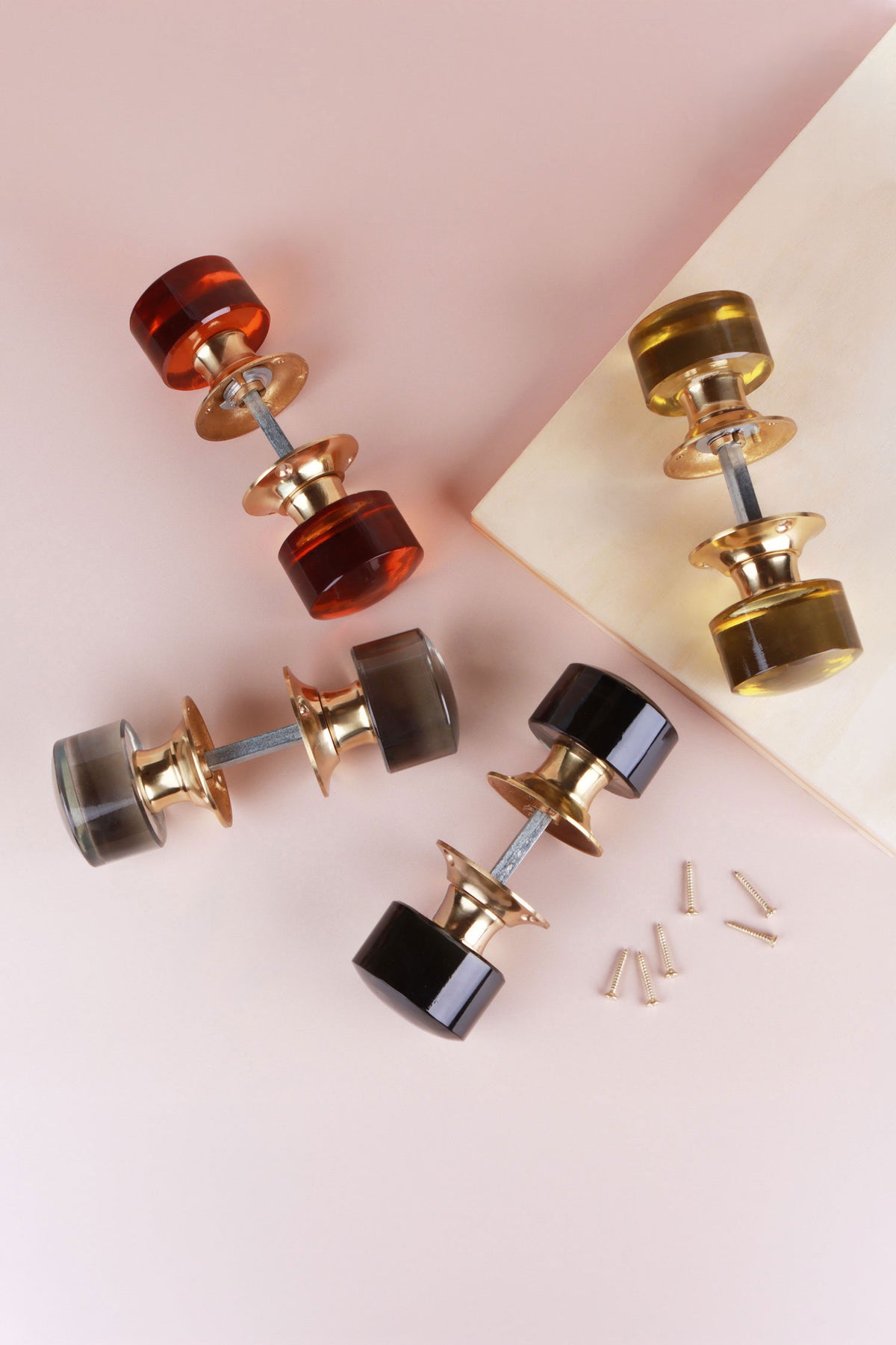 Four pairs of cylinder glass mortice door knobs joined on their spindles, in amber, ivory, clear crystal and smokey grey