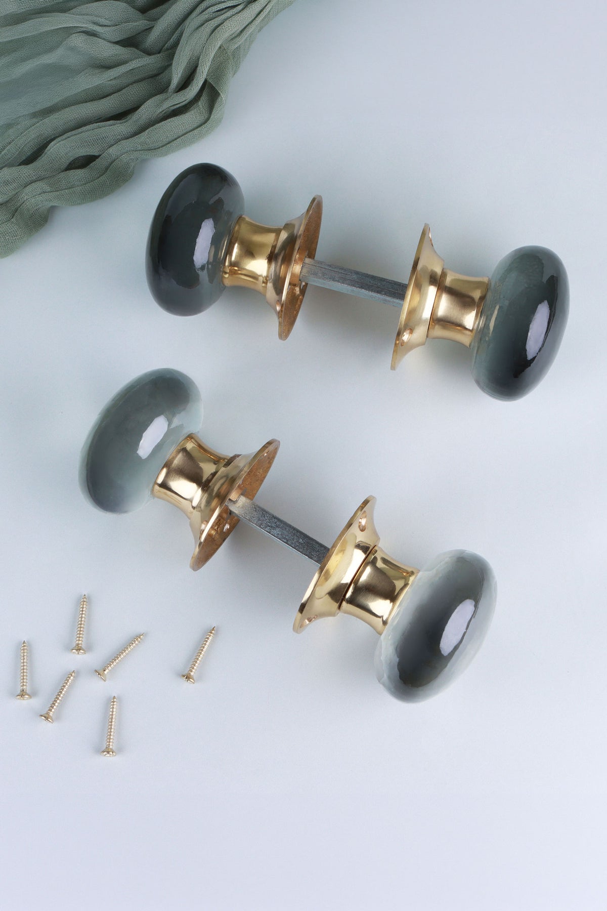 A smokey grey pair and a clear crystal pair of dome glass mortice door knobs, each joined on its spindle through the polished brass roses