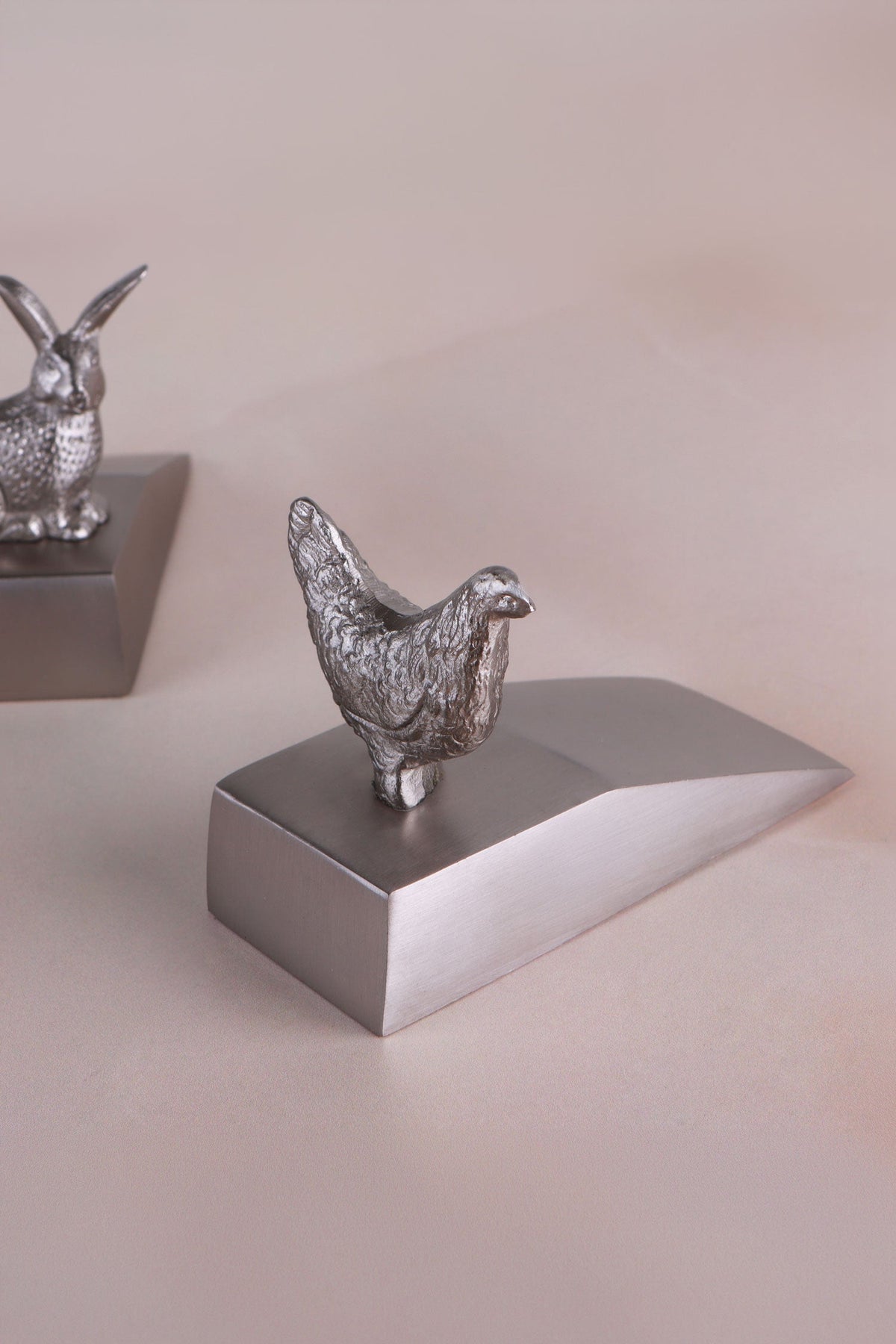 Hen door stopper in chrome on a weighted wedge base