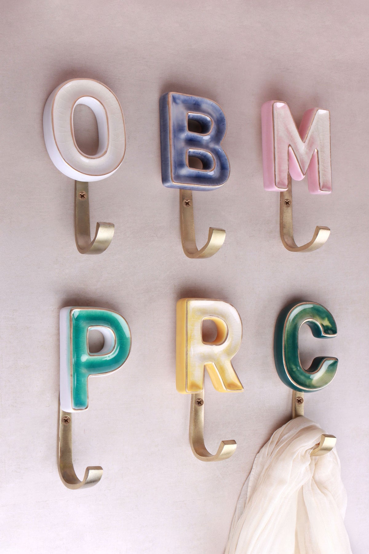 Ceramic letter hooks in blue, yellow, green and pink, mixed on one wall