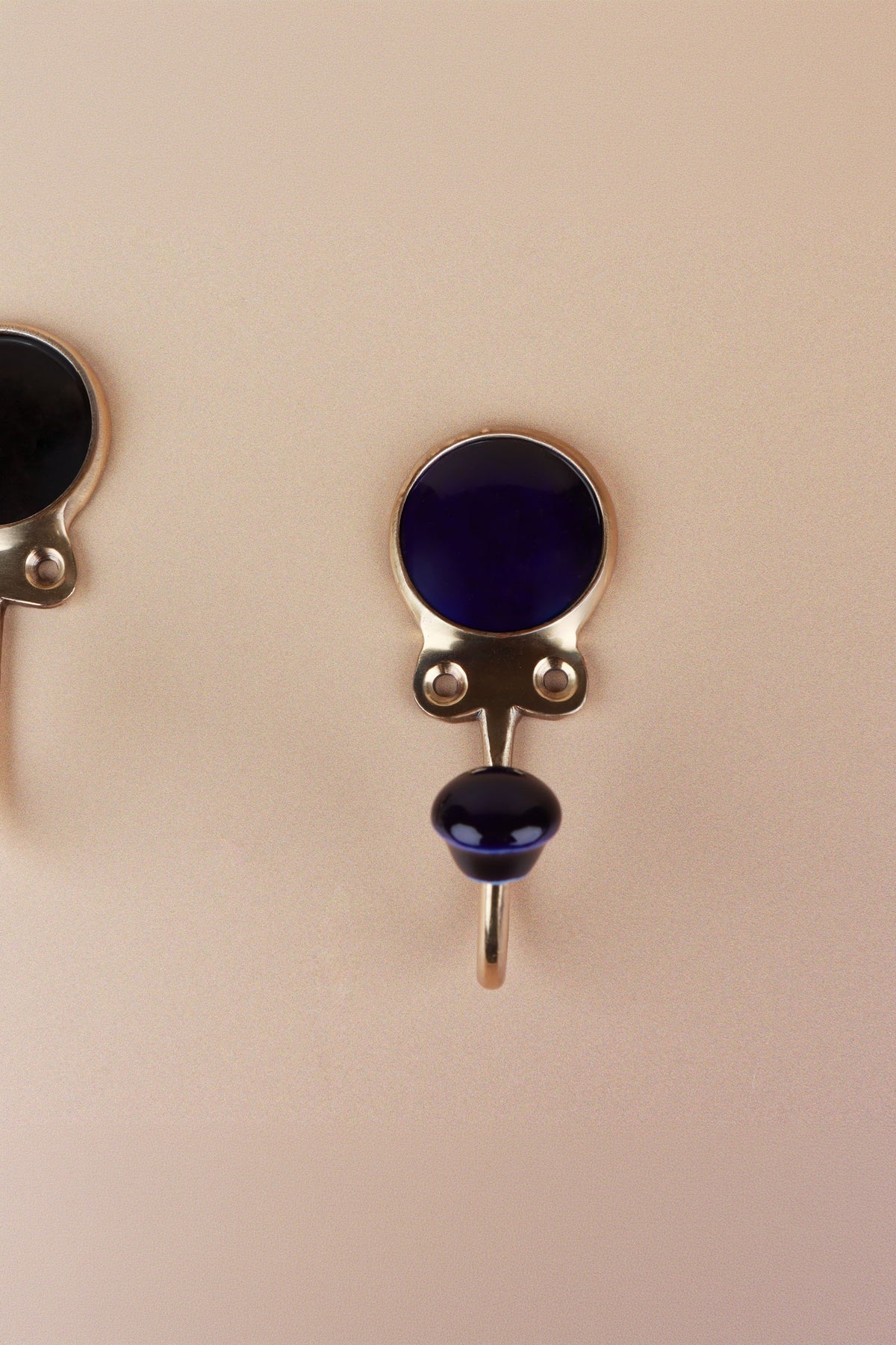 Dark blue ceramic coat hook: deep navy blue disc in a gold-tone frame with a matching dark blue ceramic knob