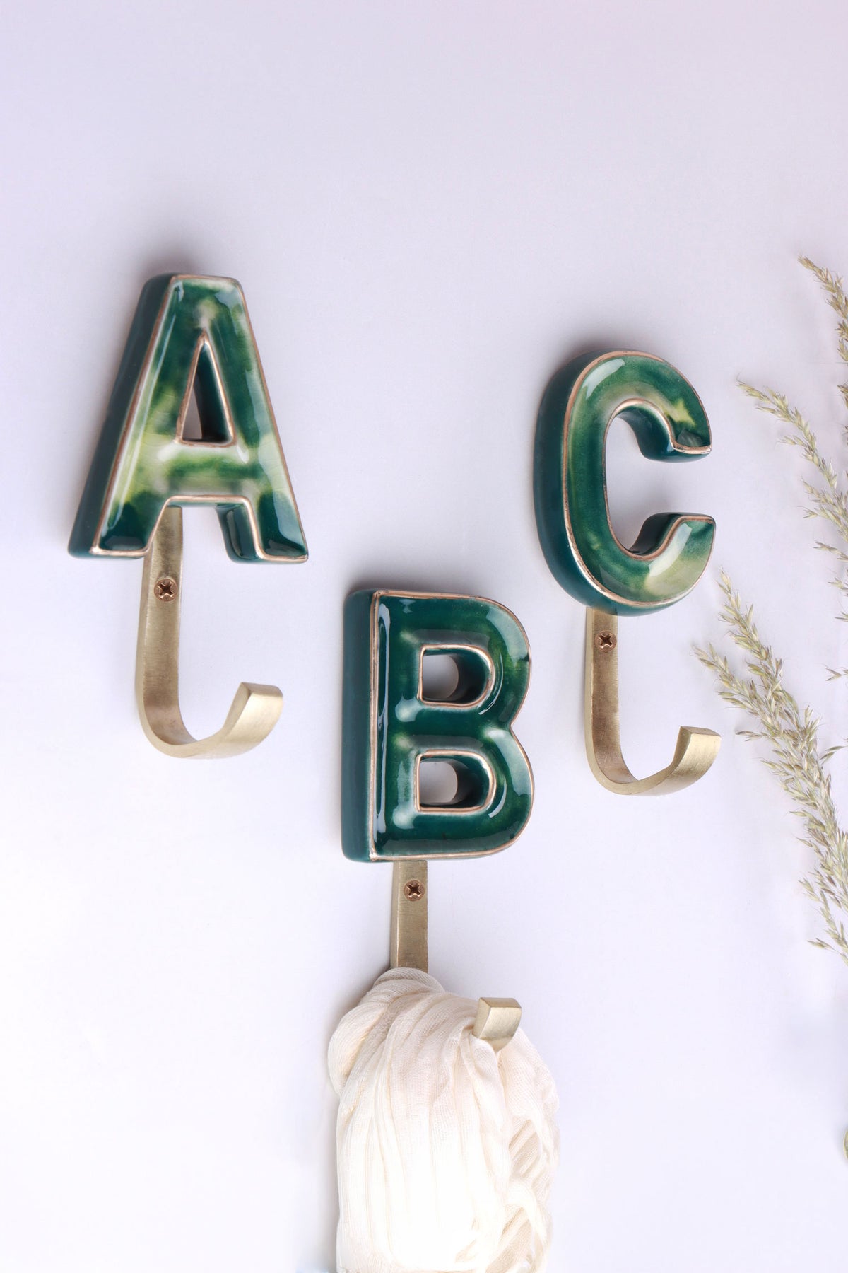 Green ceramic letter wall hooks with gold rims on gold-tone hooks