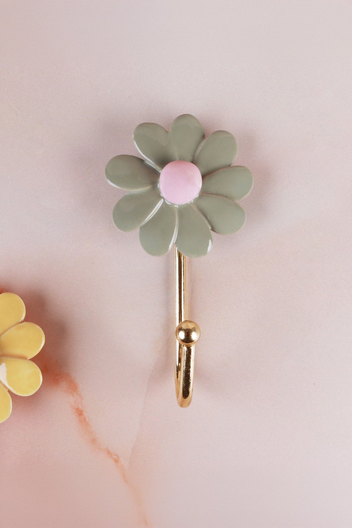 Sage green ceramic daisy wall hook with a pink centre on a gold-tone metal hook