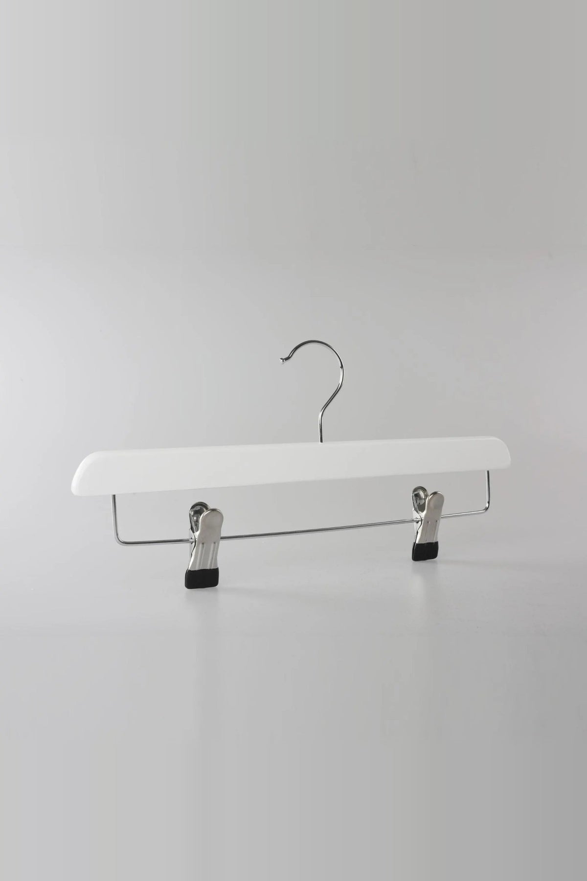 White wooden clip hanger with a metal hook and two clips, seen from an angle