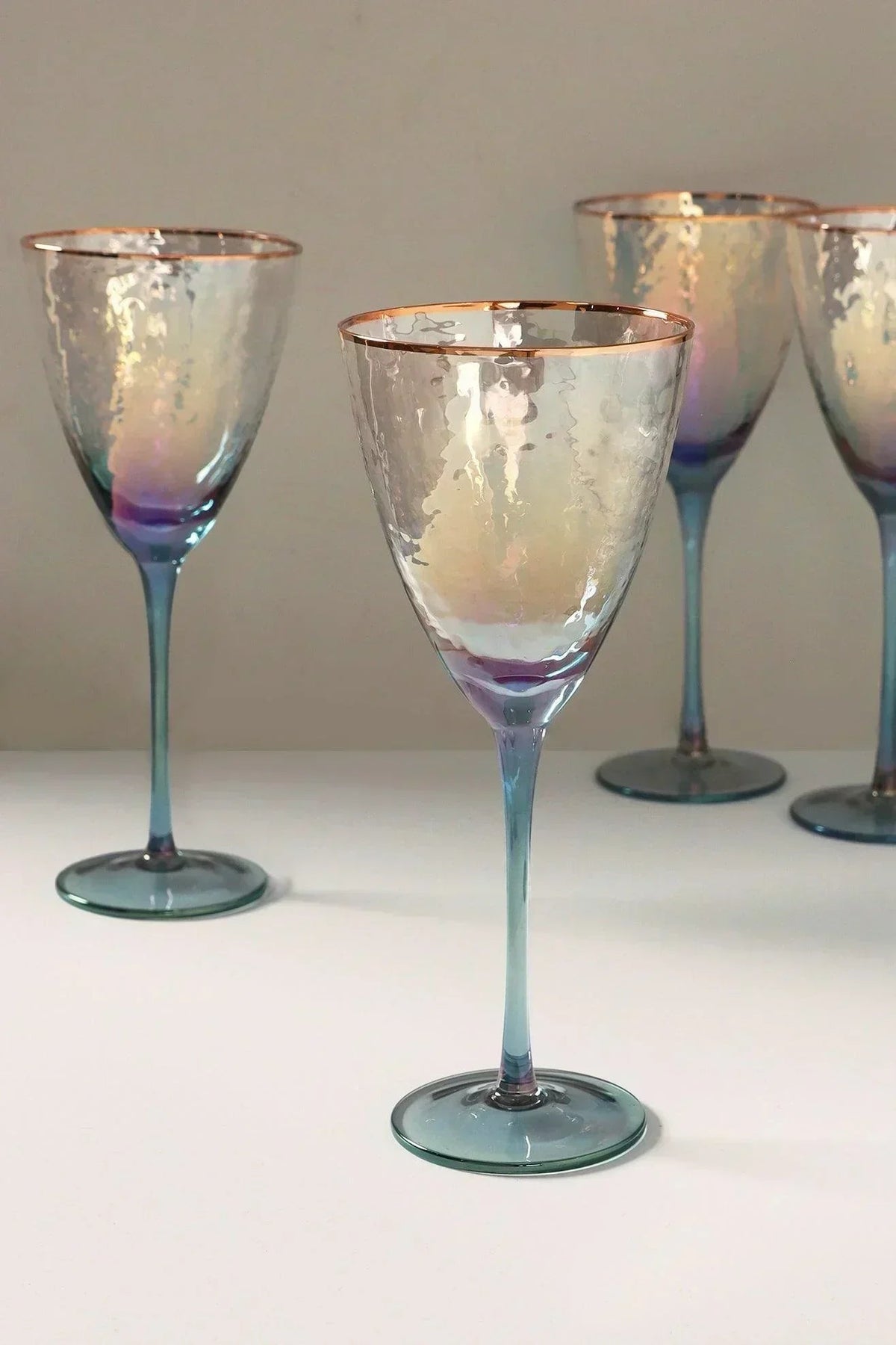 The glassware edit — a set of four handmade iridescent grey hammered wine glasses, set against a candlelit hosting table | G Decor