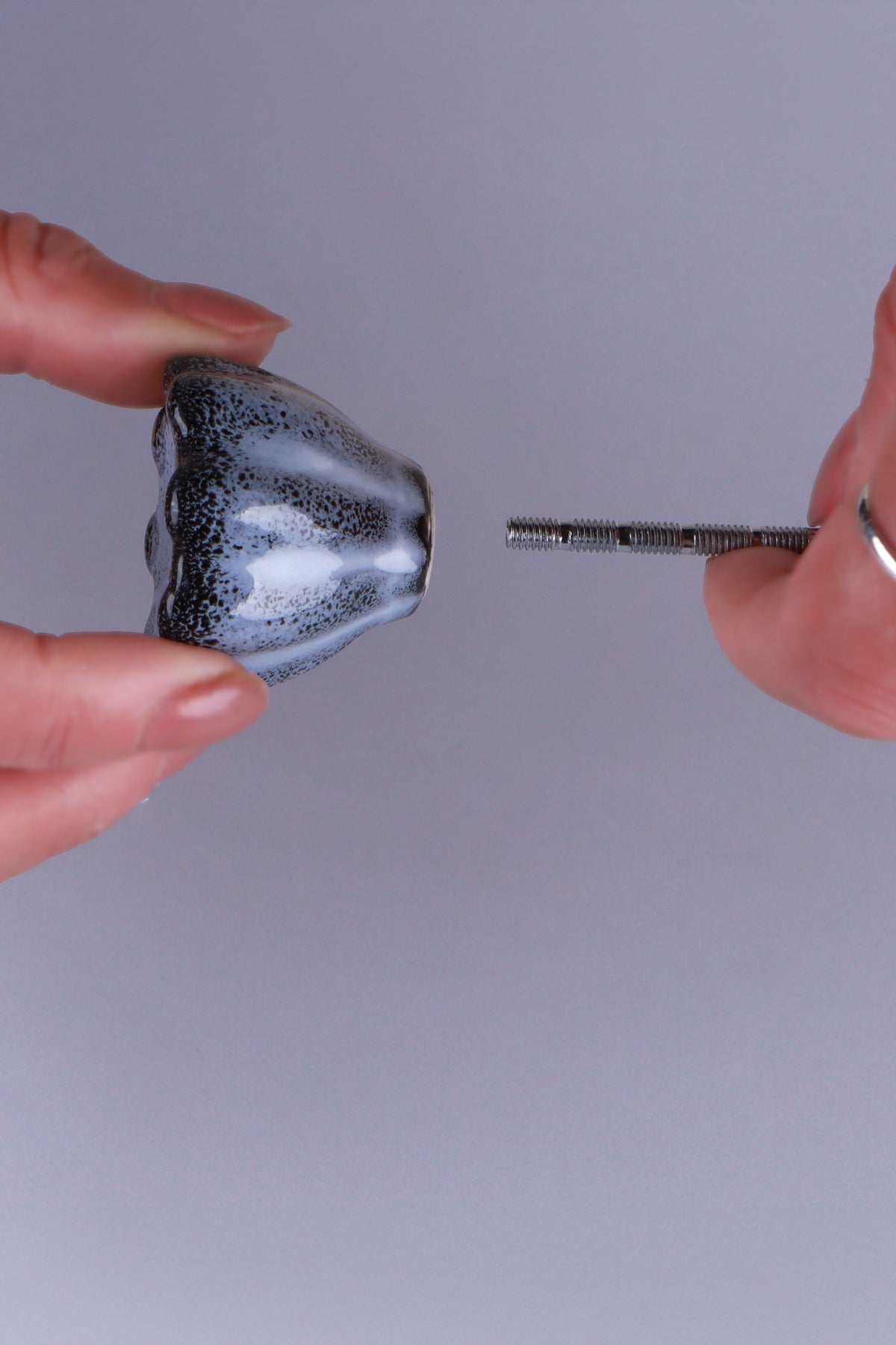 Black ceramic knob held between the fingers with its M4 bolt, to show the size