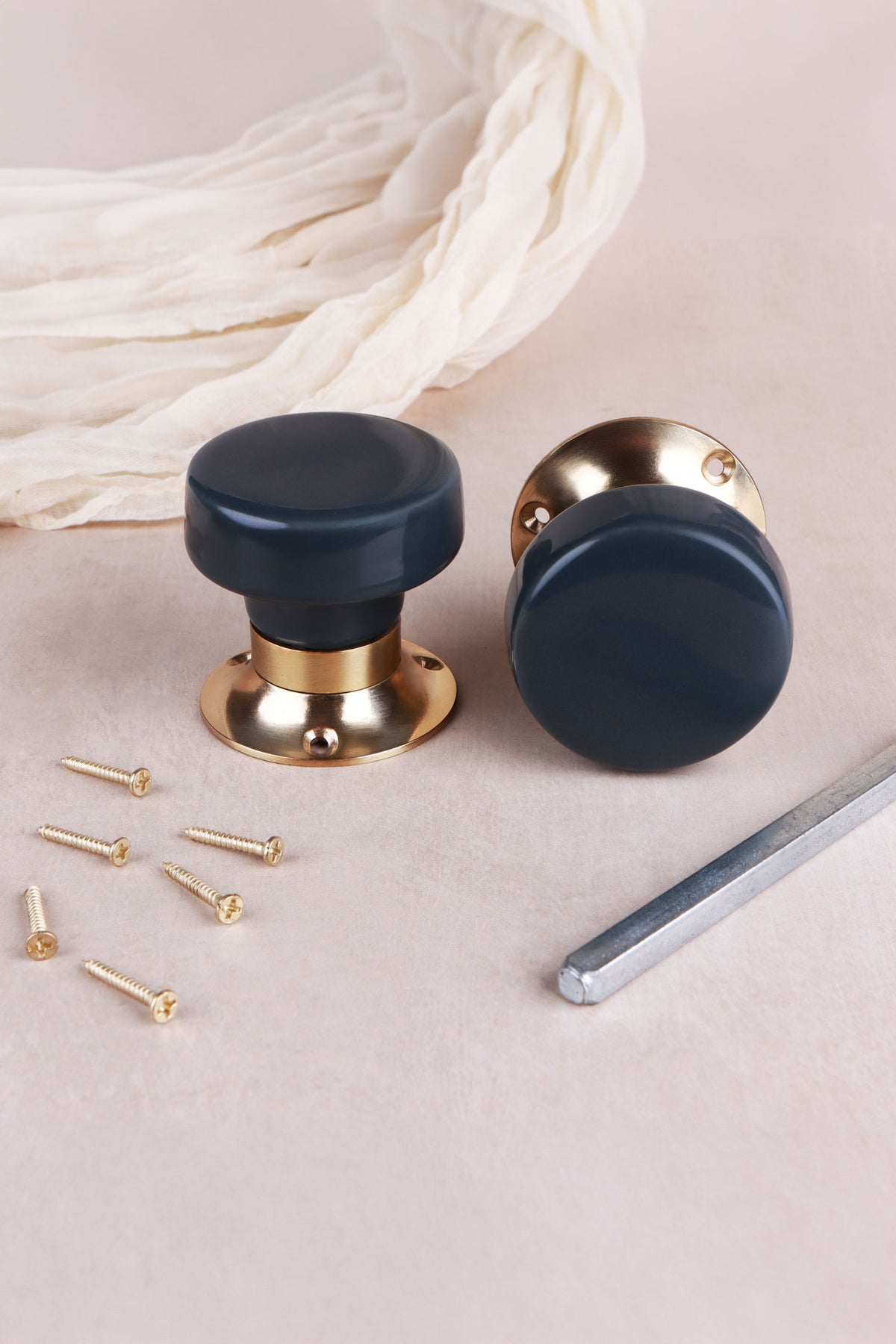 Pair of charcoal ceramic mortice door knobs with flat faces on polished brass roses, with the 8 mm spindle and fixing screws