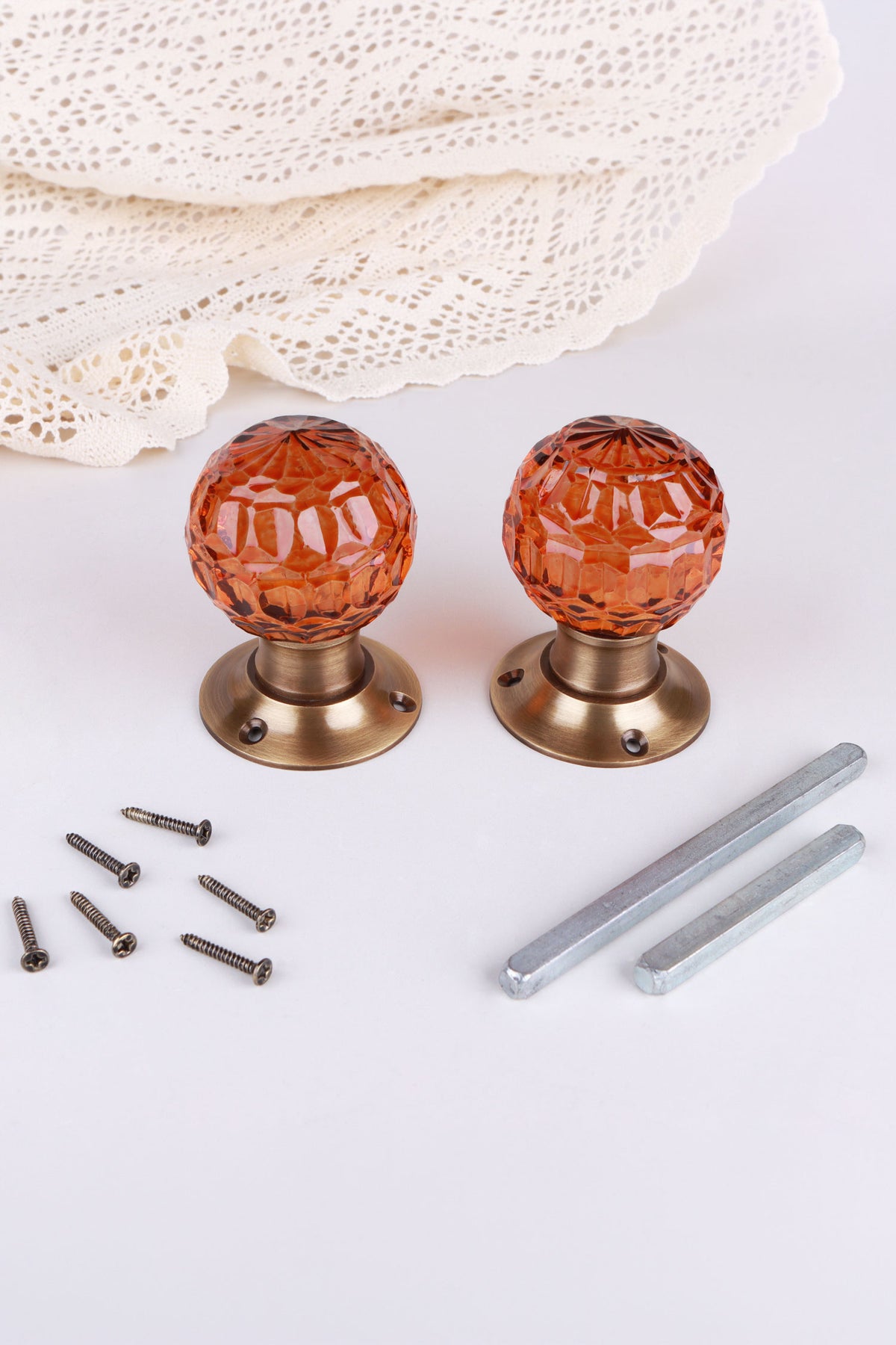 Pair of amber faceted glass mortice door knobs on antique brass roses, with the square spindles and fixing screws