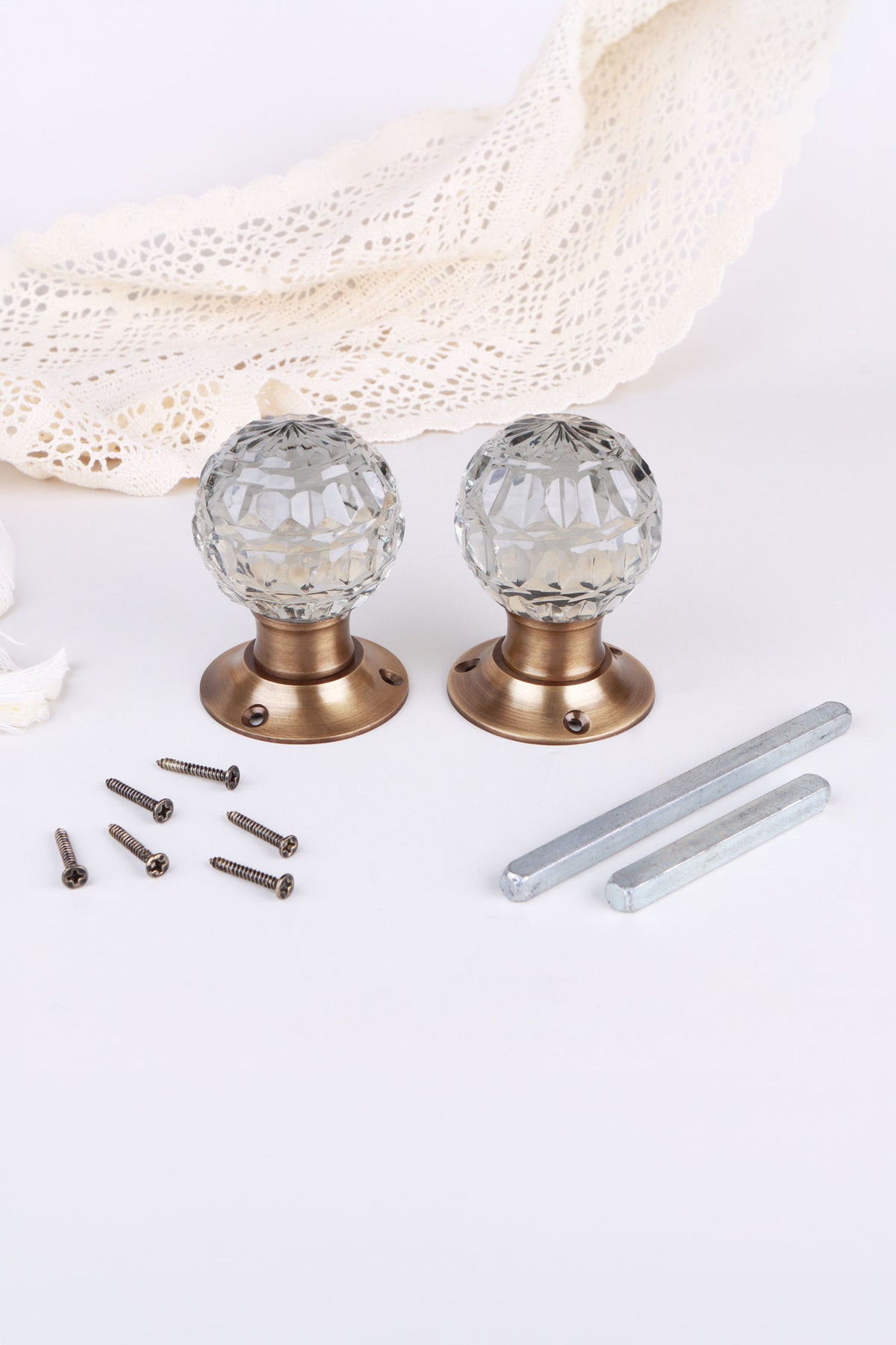 Pair of clear crystal faceted glass mortice door knobs on antique brass roses, with the square spindles and fixing screws