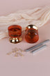 Pair of amber glass cylinder mortice door knobs on polished brass roses, one standing and one on its side, with the square spindles and fixing screws