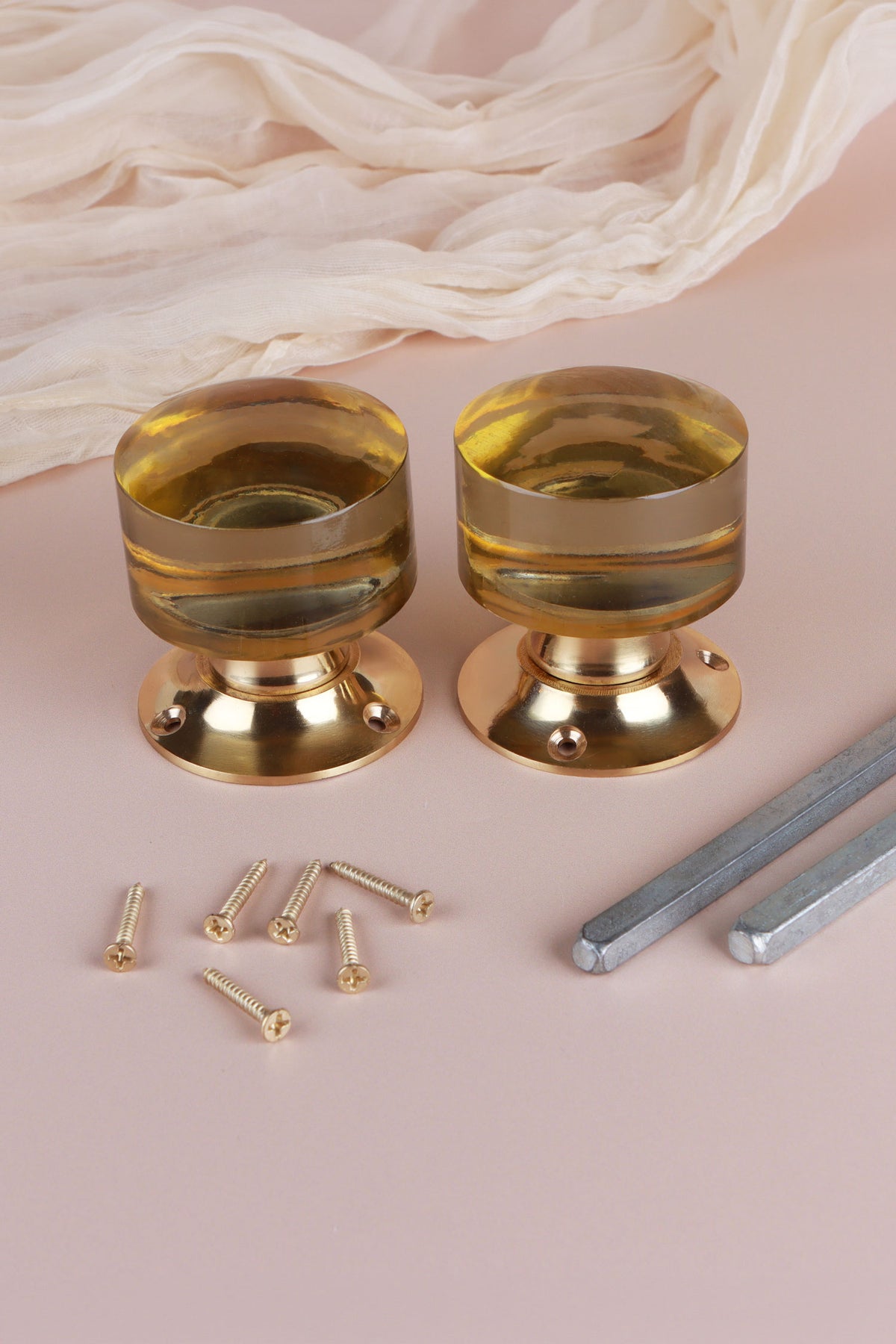 Two ivory glass cylinder door knobs standing on their polished brass roses, with the square spindles and fixing screws