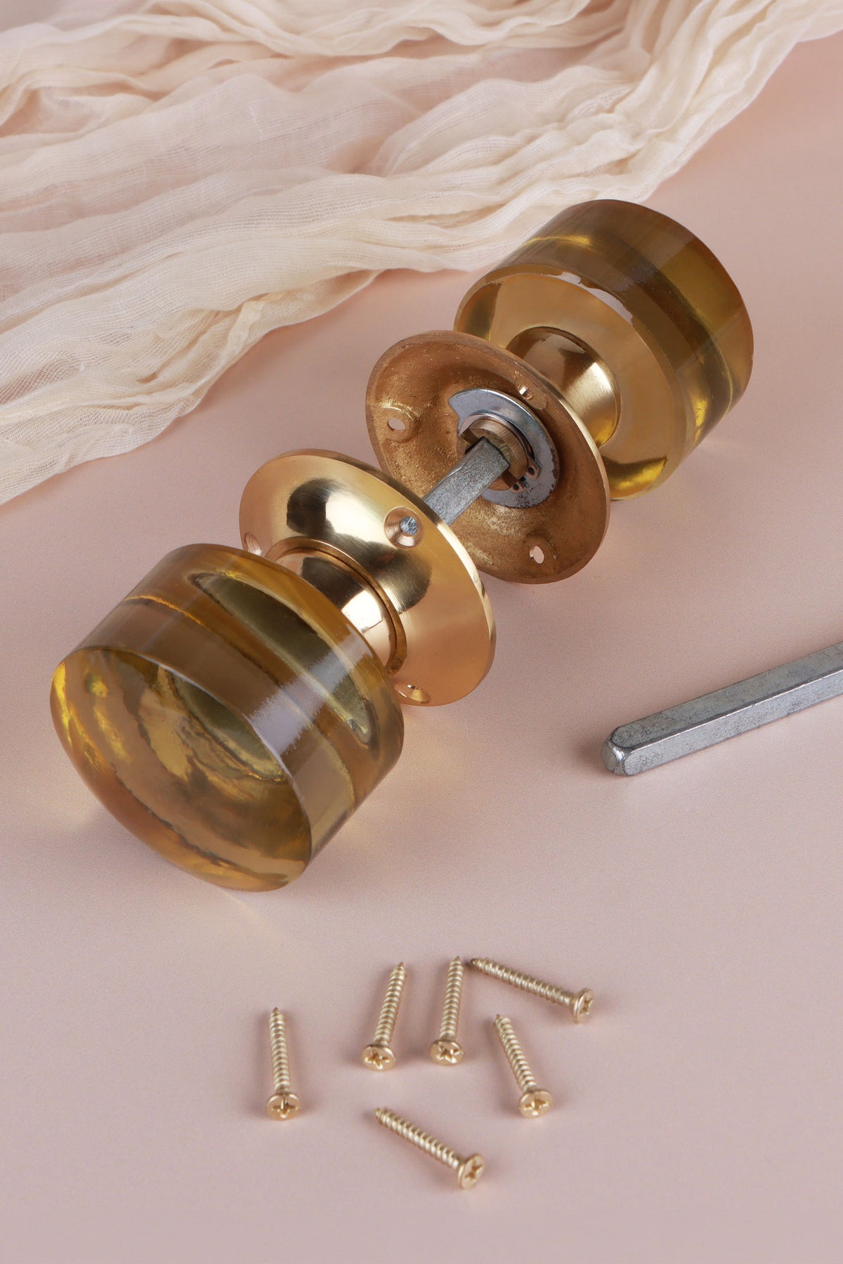 Ivory glass cylinder mortice door knobs joined by the spindle through their polished brass roses, as they sit on a door