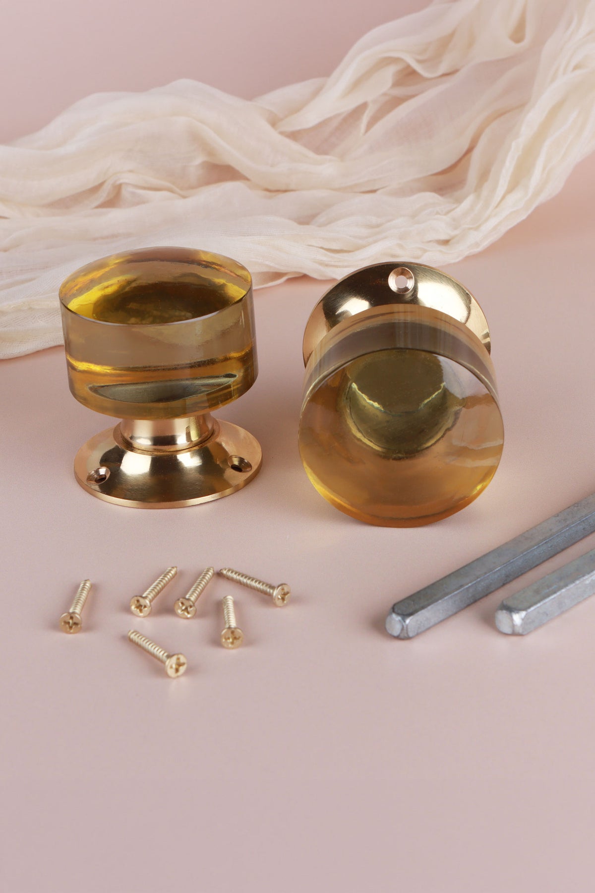 Pair of ivory glass cylinder mortice door knobs on polished brass roses, one standing and one on its side, with the square spindles and fixing screws