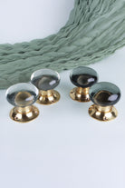 Four dome glass door knobs on polished brass roses, two in clear crystal and two in smokey grey