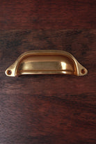 Deep scoop aged brass cup pull, 4 inch, with exposed fixing lugs and no backplate