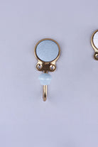 Blue-grey crackle glaze ceramic coat hook: pale blue-grey disc with fine crackle lines in a gold-tone frame, with a pale blue knob