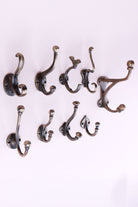 The nine cast iron hooks in antique brass finish set out in rows of three, seen from the side