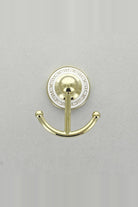 Gold double robe hook with two arms on a round white wall plate with a gold Greek key border