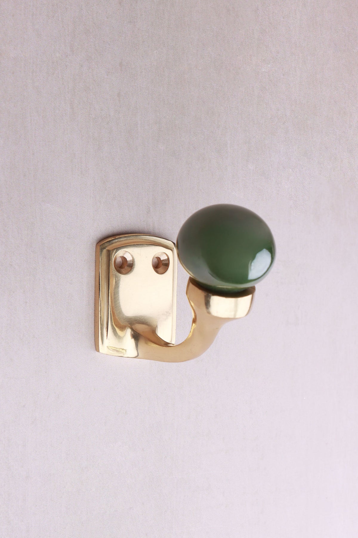 Green ceramic ball hook: a deep green ceramic ball on a curved brass-finish hook with a small back plate and two screws