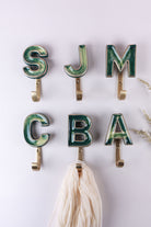 Green ceramic letter hooks on the wall, third view