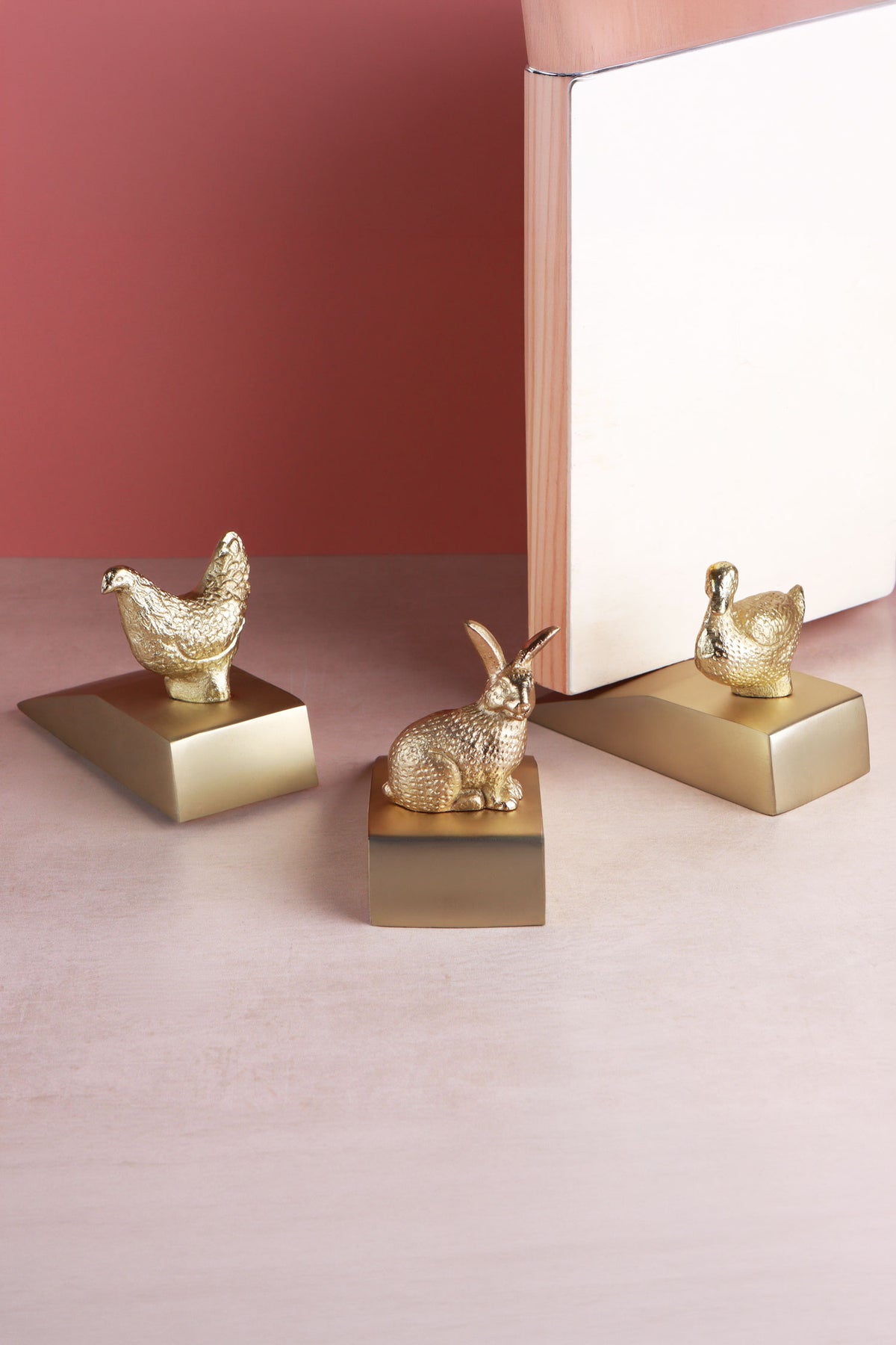 Homestead duck, hen and rabbit door stoppers in polished brass beside an interior door