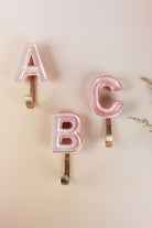 Pink ceramic letter hooks on the wall, second view