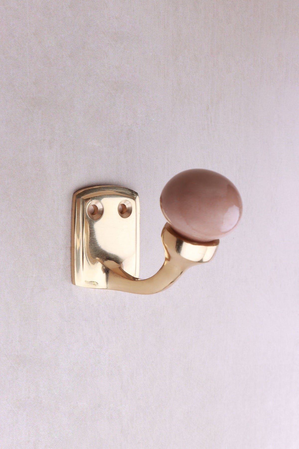 Rosy brown ceramic ball hook: a dusky rose-brown ceramic ball on a curved brass-finish hook with a small back plate and two screws