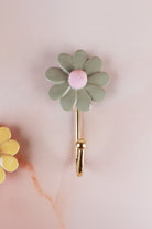 Sage green ceramic daisy wall hook with a pink centre on a gold-tone metal hook