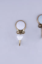 White crackle glaze ceramic coat hook: white disc with fine grey crackle lines in a gold-tone frame, with a white crackle knob